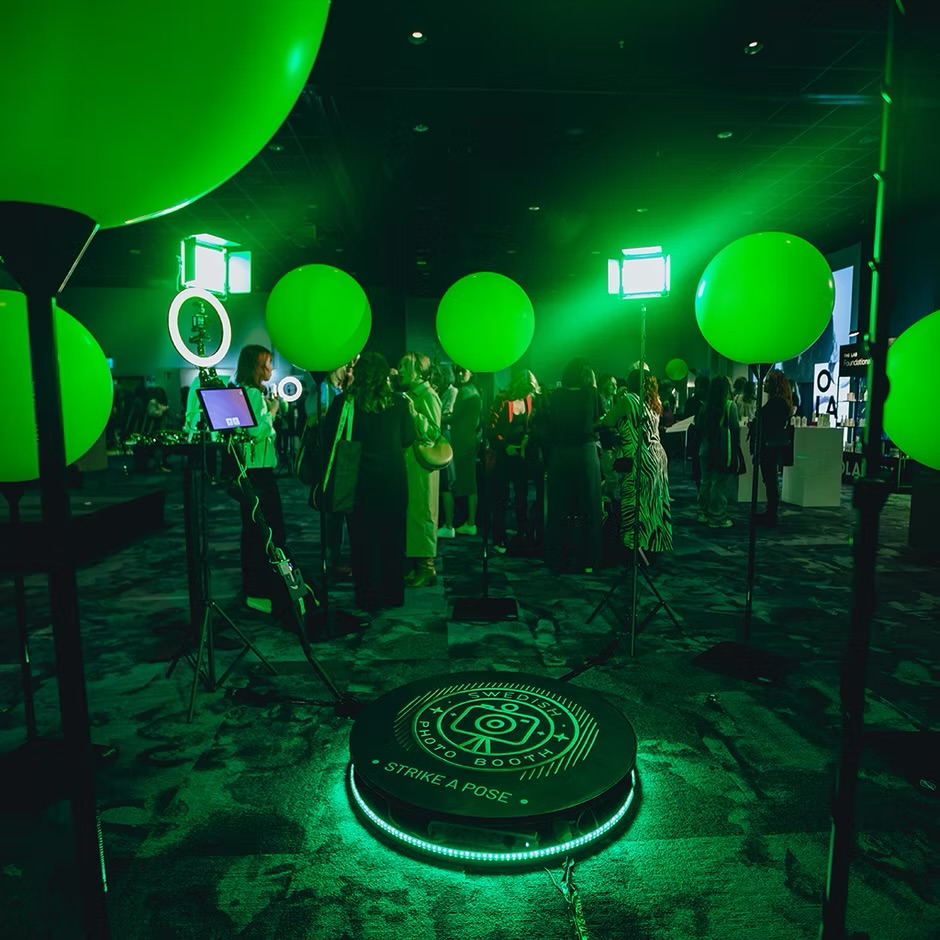 360-fotobås med grönt eventljus och ballonger bland gäster